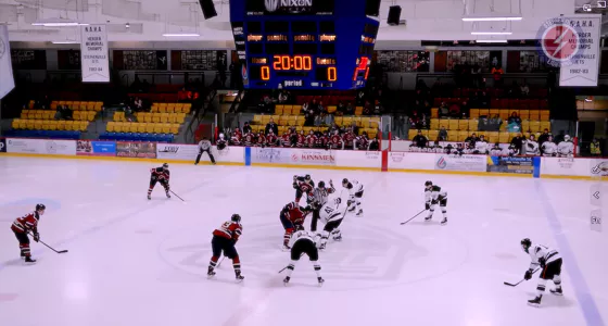 Ice hockey game in action as players in red uniforms go for a goal on indoor rink